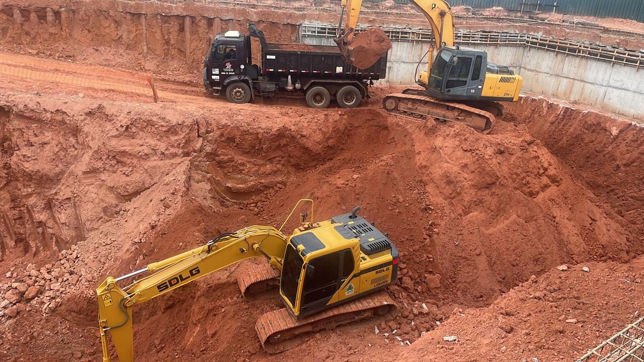 Caminhão basculante sendo carregado em escavação profunda