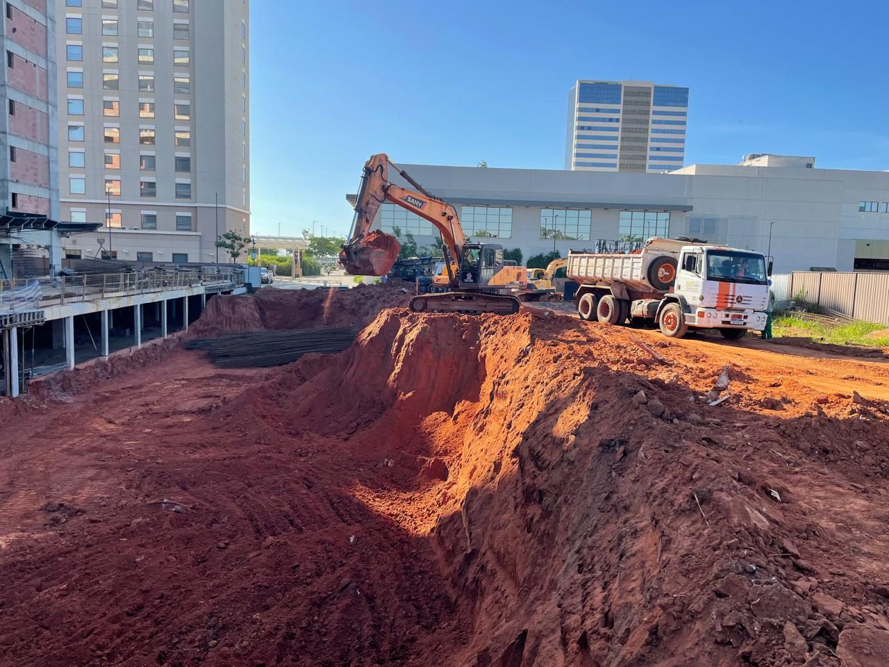 Carregamento de caminhão basculante ao entardecer em obra urbana